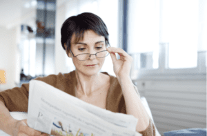 Mid woman Reading newspaper with eyeglasses