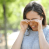 Woman rubbing her eyes standing outdoors in a park