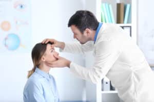 Ophthalmologist looking closely at a young woman's eye during a consultation leading up to vision correction treatment.