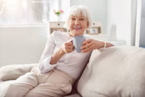 Older woman relaxes on the couch with a cup of coffee.