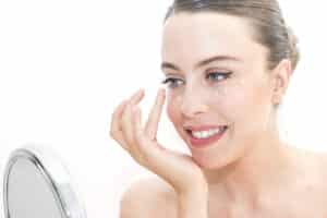 Woman applies cream to the bags under her eyes.